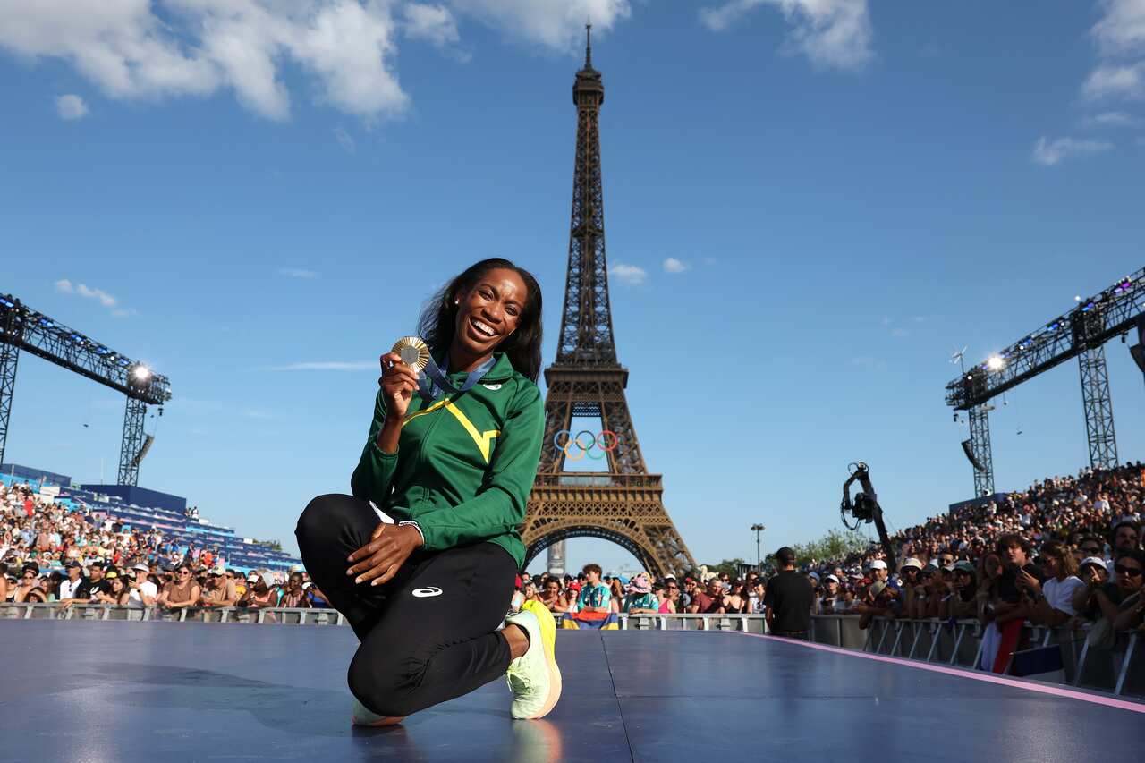 Thea LaFond poses with a gold medal. The Eiffel Tower is behind her and crowds surround the stage she is on.
