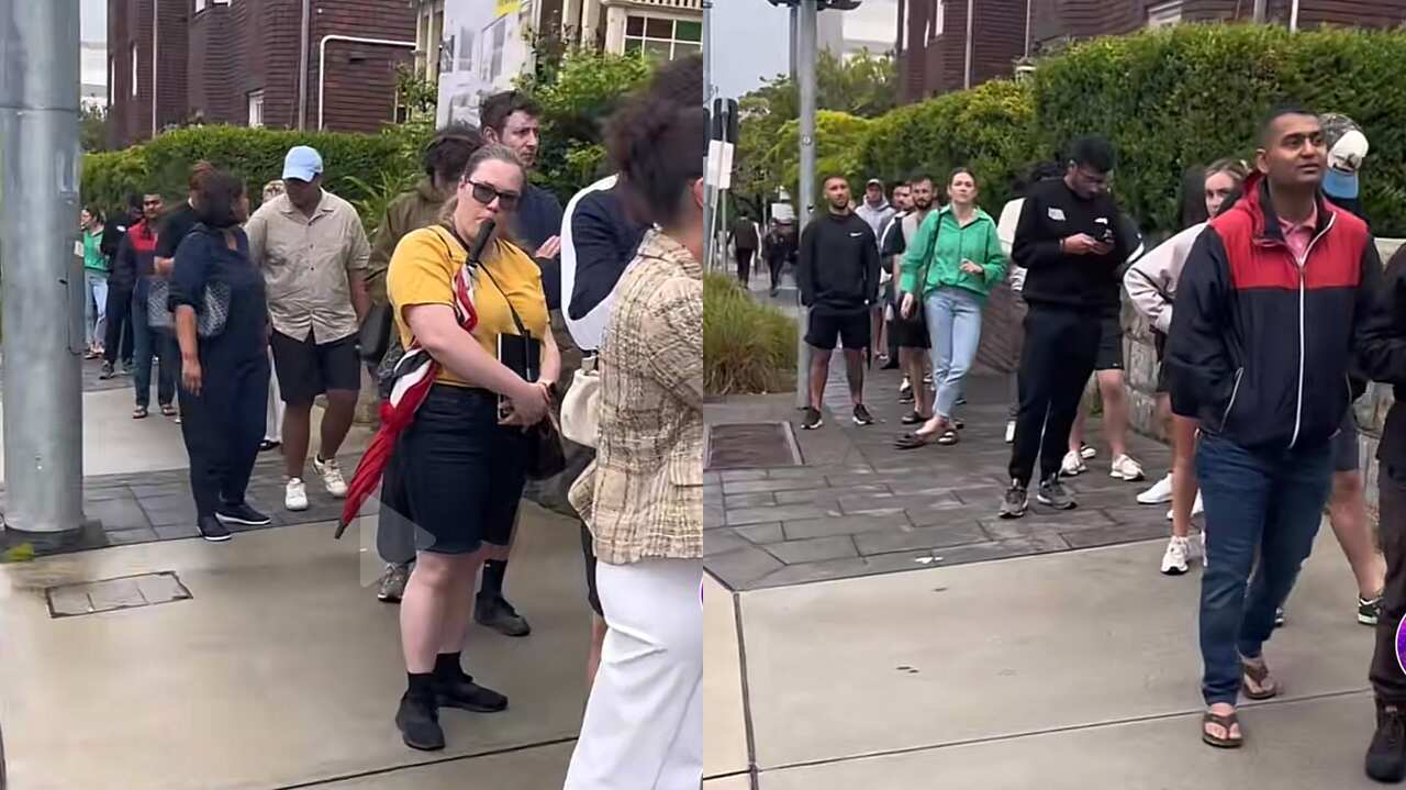 People waiting in line on a street.