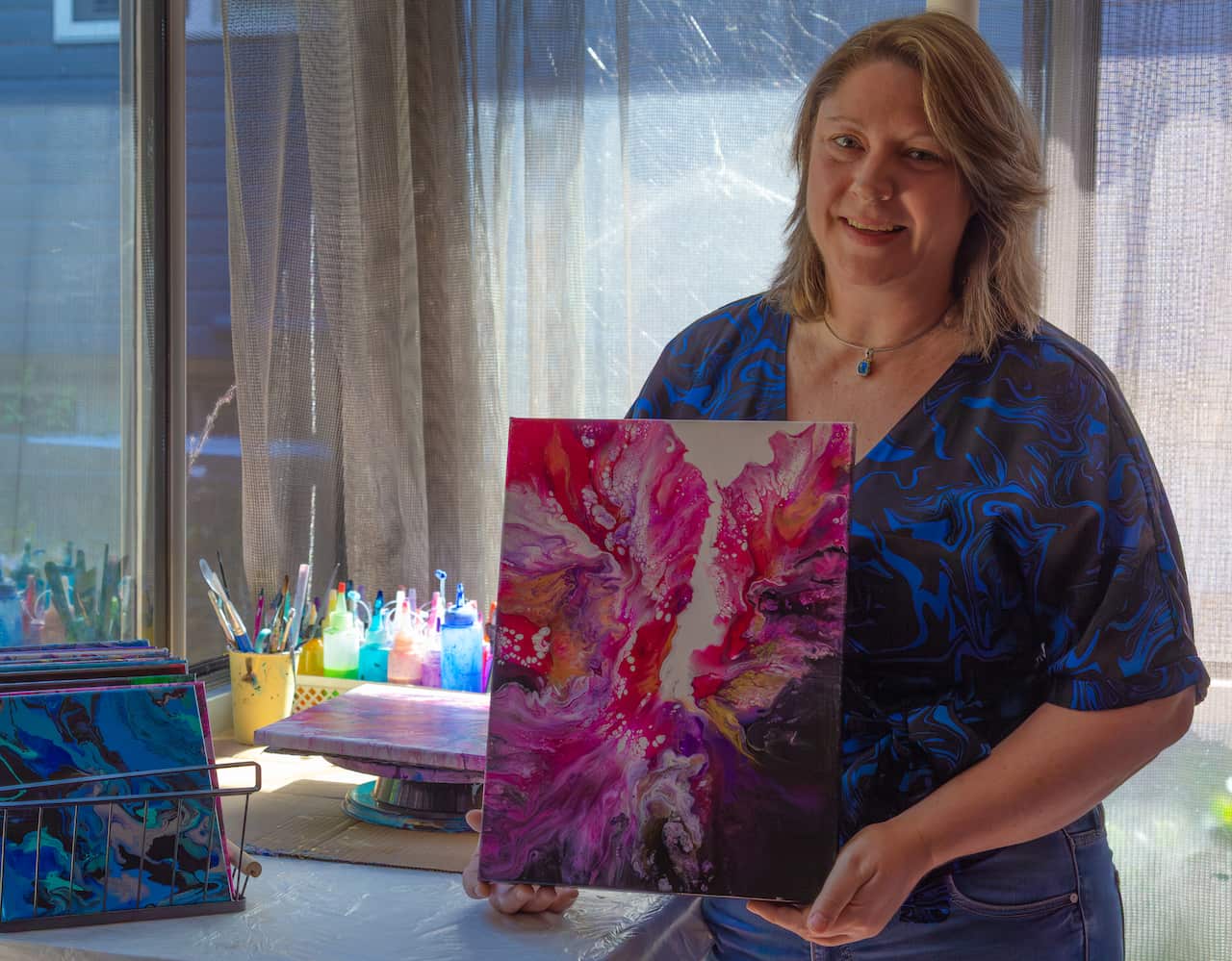 A woman holding a piece of art in her studio.