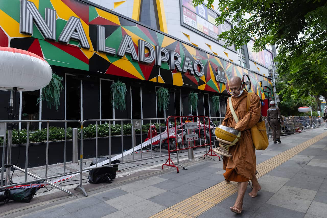 A monk walks past a fenced of pub in Thailand