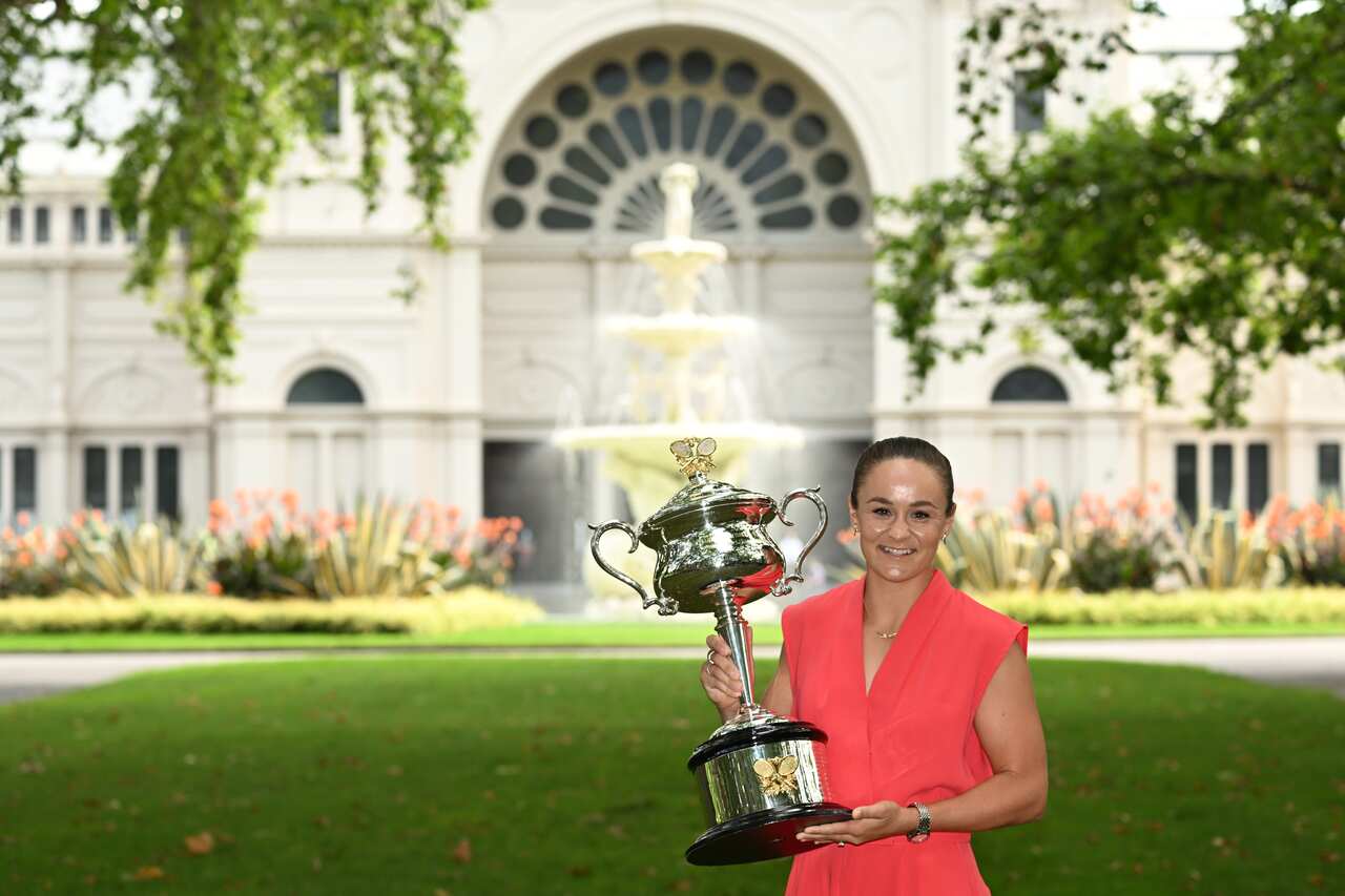 Ash Barty is seen holding a trophy and posing for a photograph.