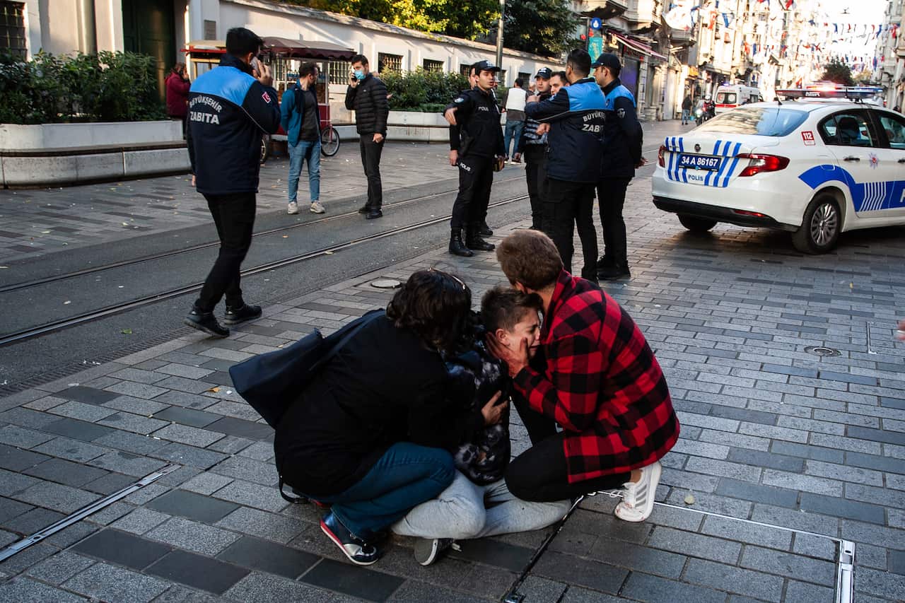 A young boy crying on the ground as he is cared for by a man and a woman.