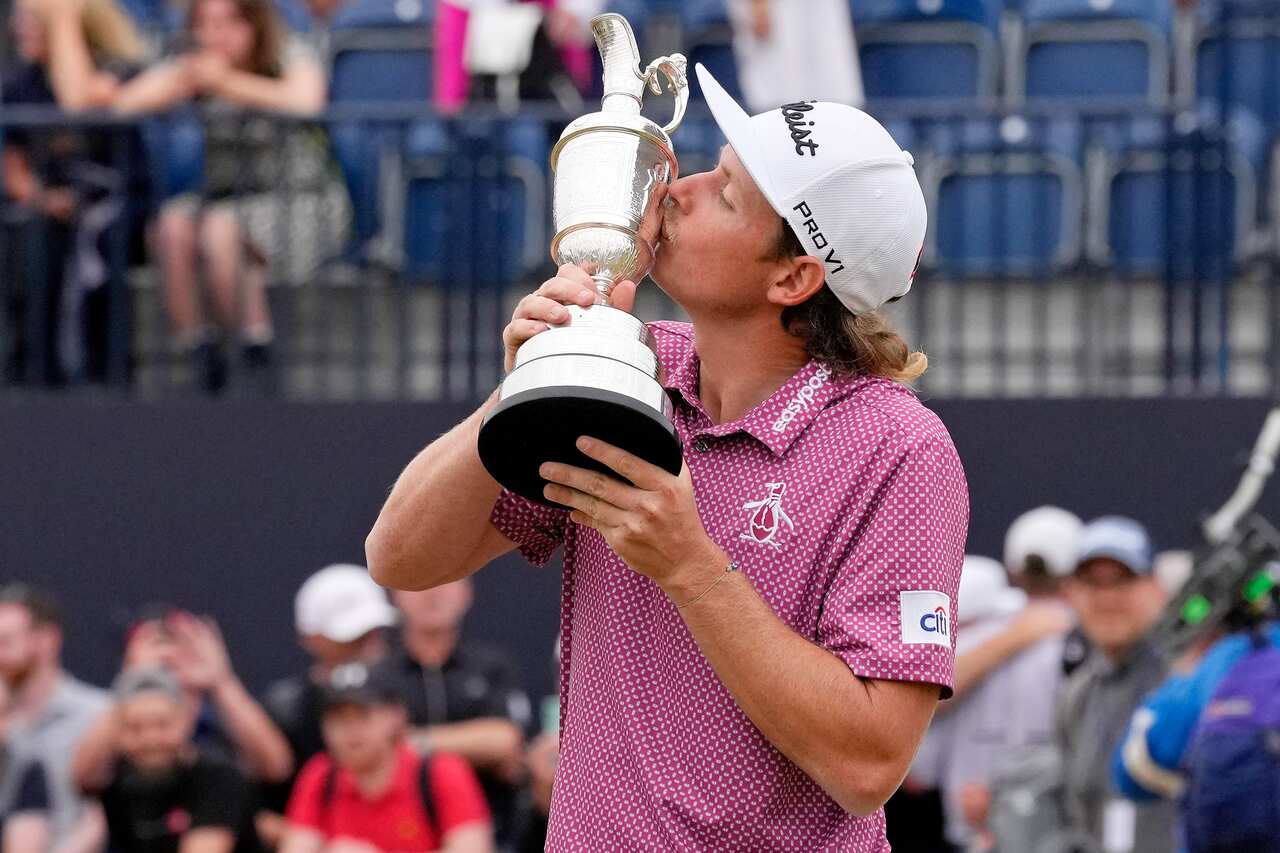 A man kissing a silver trophy in the shape of a jug.