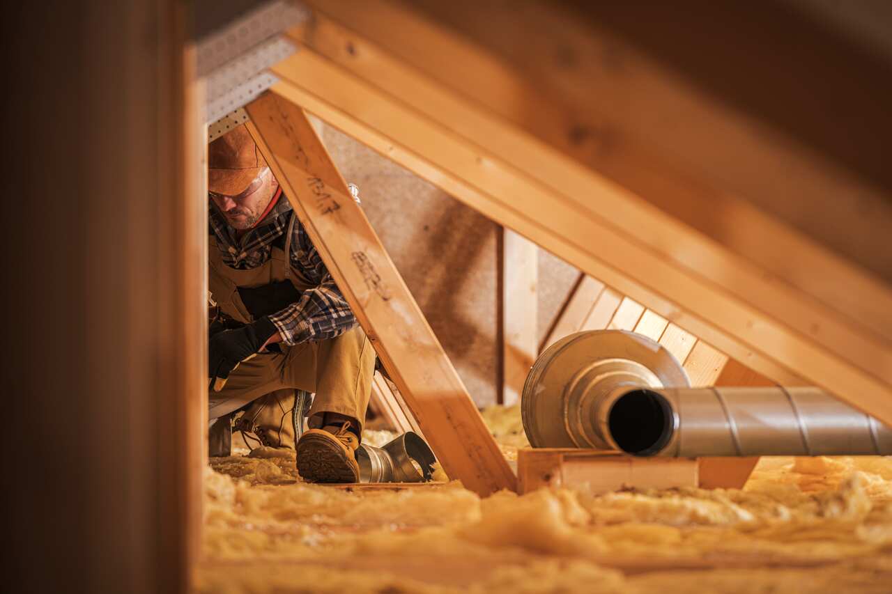 A worker in a roof space where there is insulation.