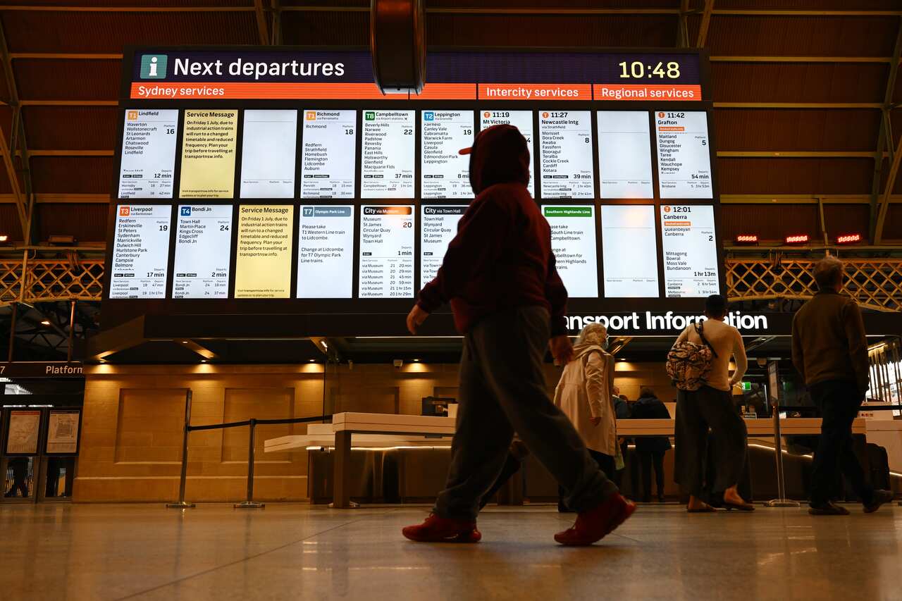 A person walking past a departures board at a train station.