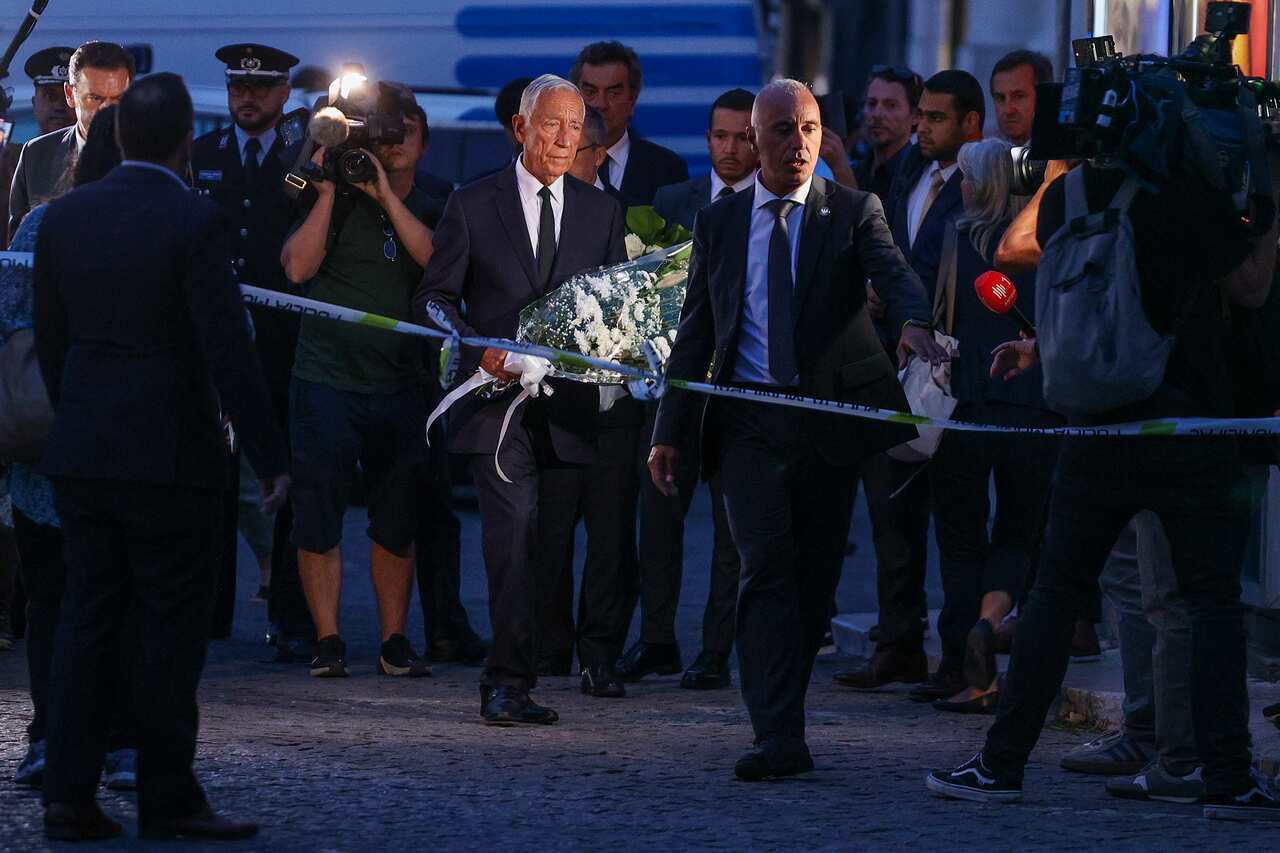A man carries flowers, paying respect to victims of a funicular crash in London. 