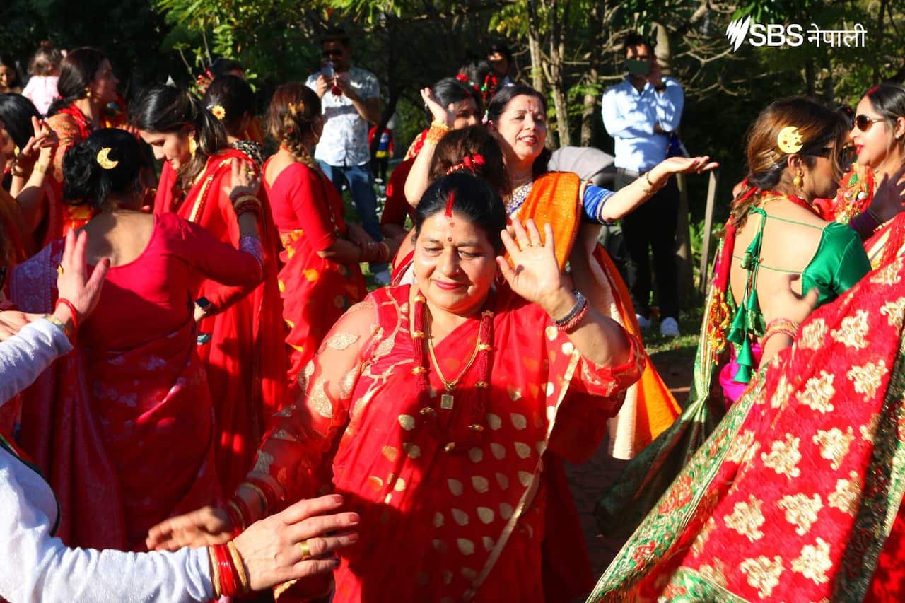 Women dressed in elaborate red and gold dresses, dance together