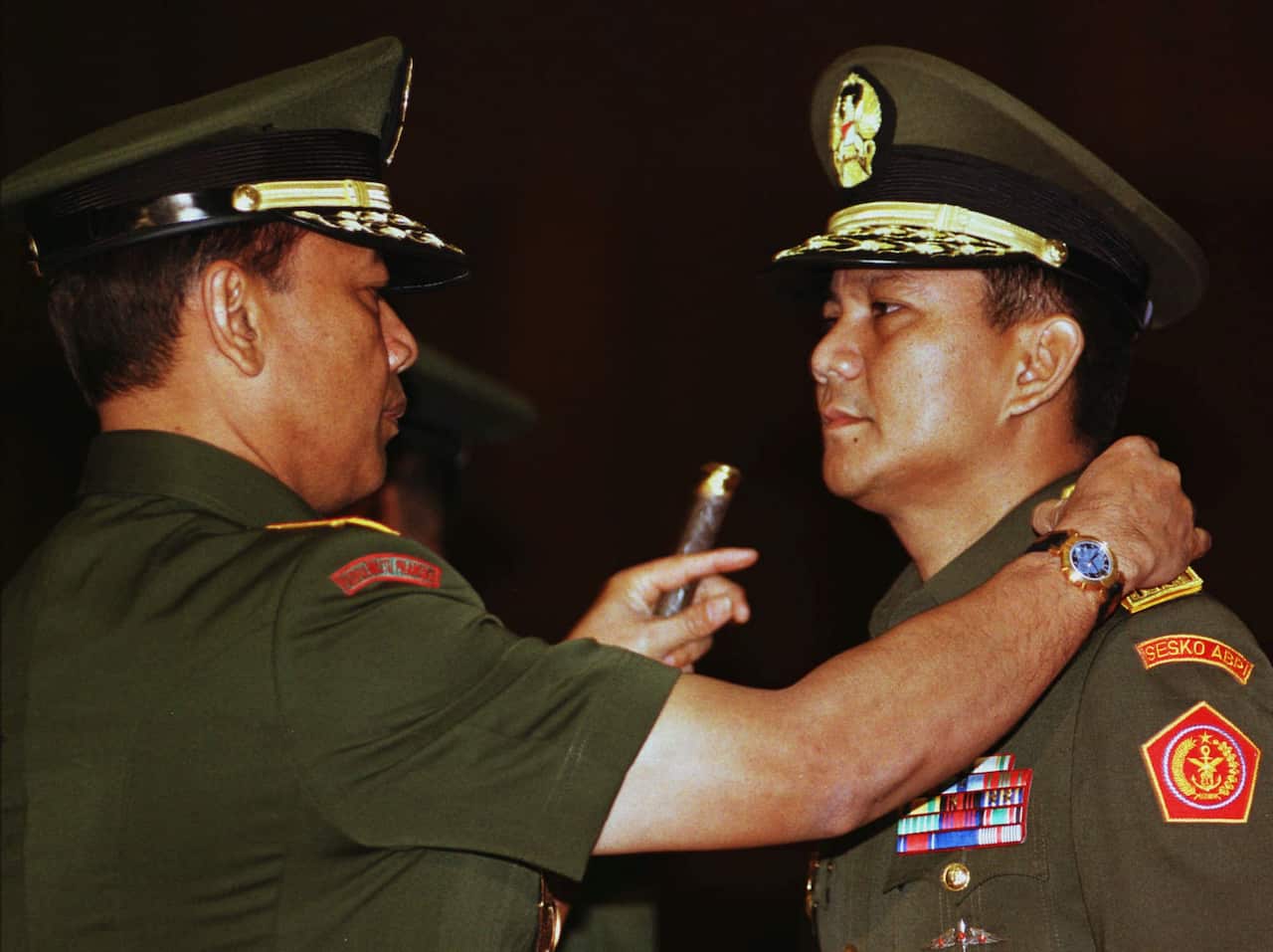 A man in a military uniform is speaking to another man in uniform, standing close.