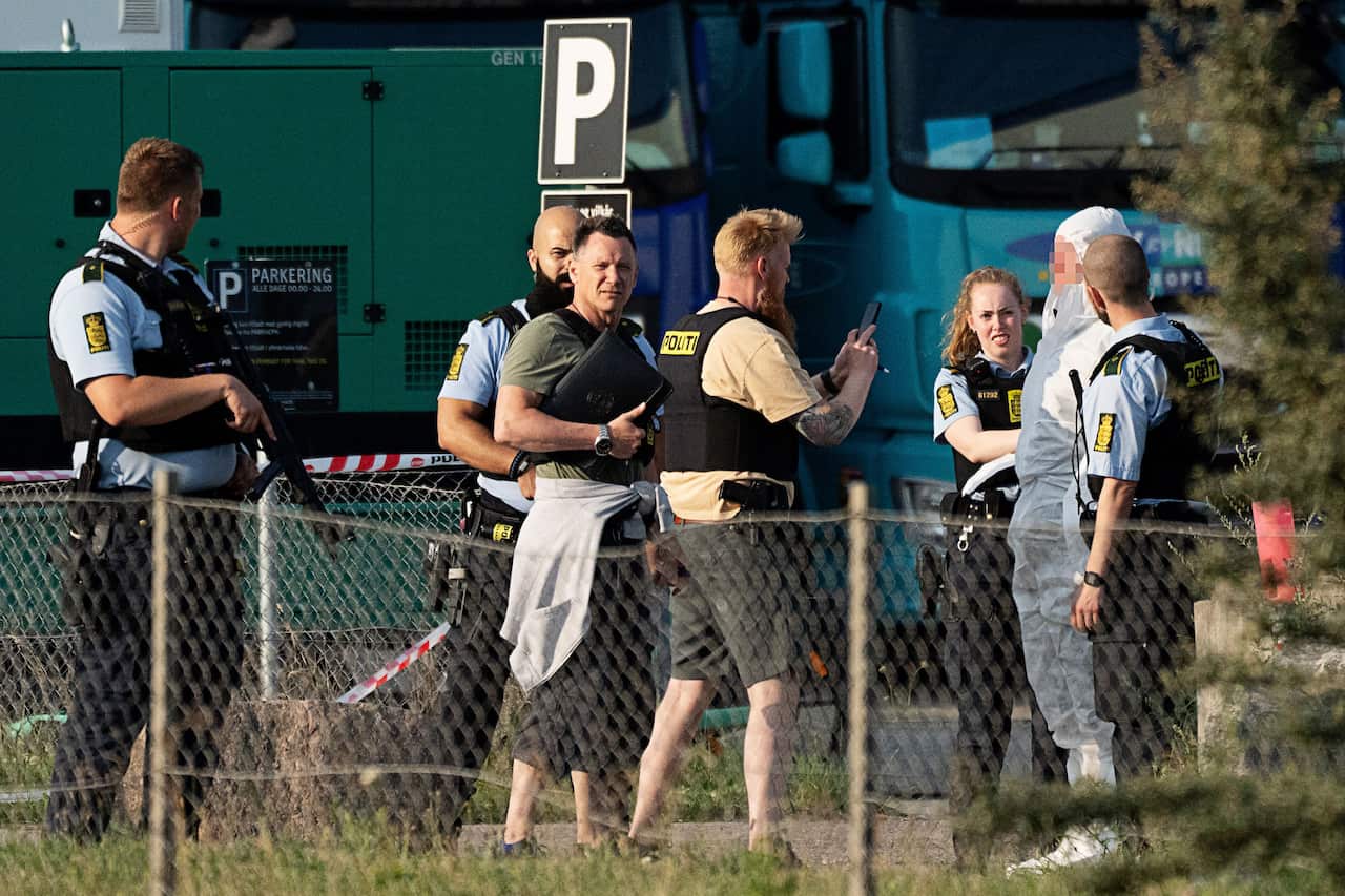 A policeman takes a picture of a man detained and believed to be the suspect at the scene of the Field's shopping centre in Copenhagen, Denmark, on 3 July 2022.