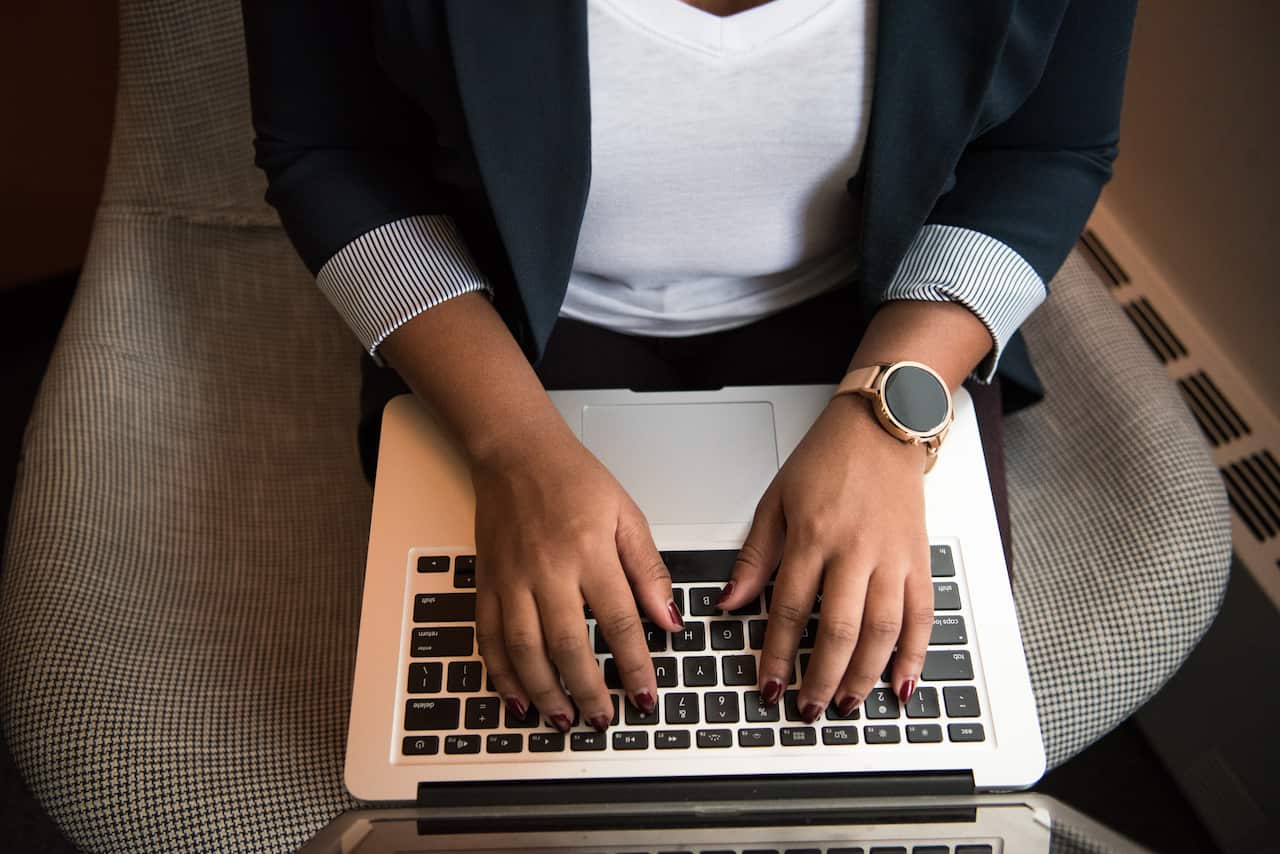 Woman sitting on a chair using her laptop, which is sitting on her lap.