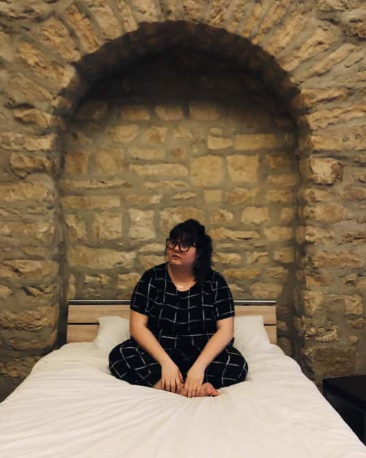 A person is sitting on a bed with their legs crossed.