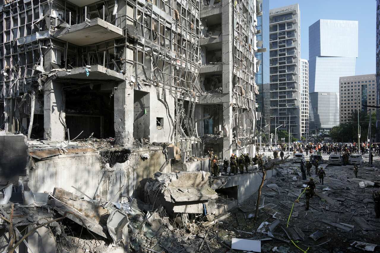 Rescue workers standing outside a building that has been severely damaged.