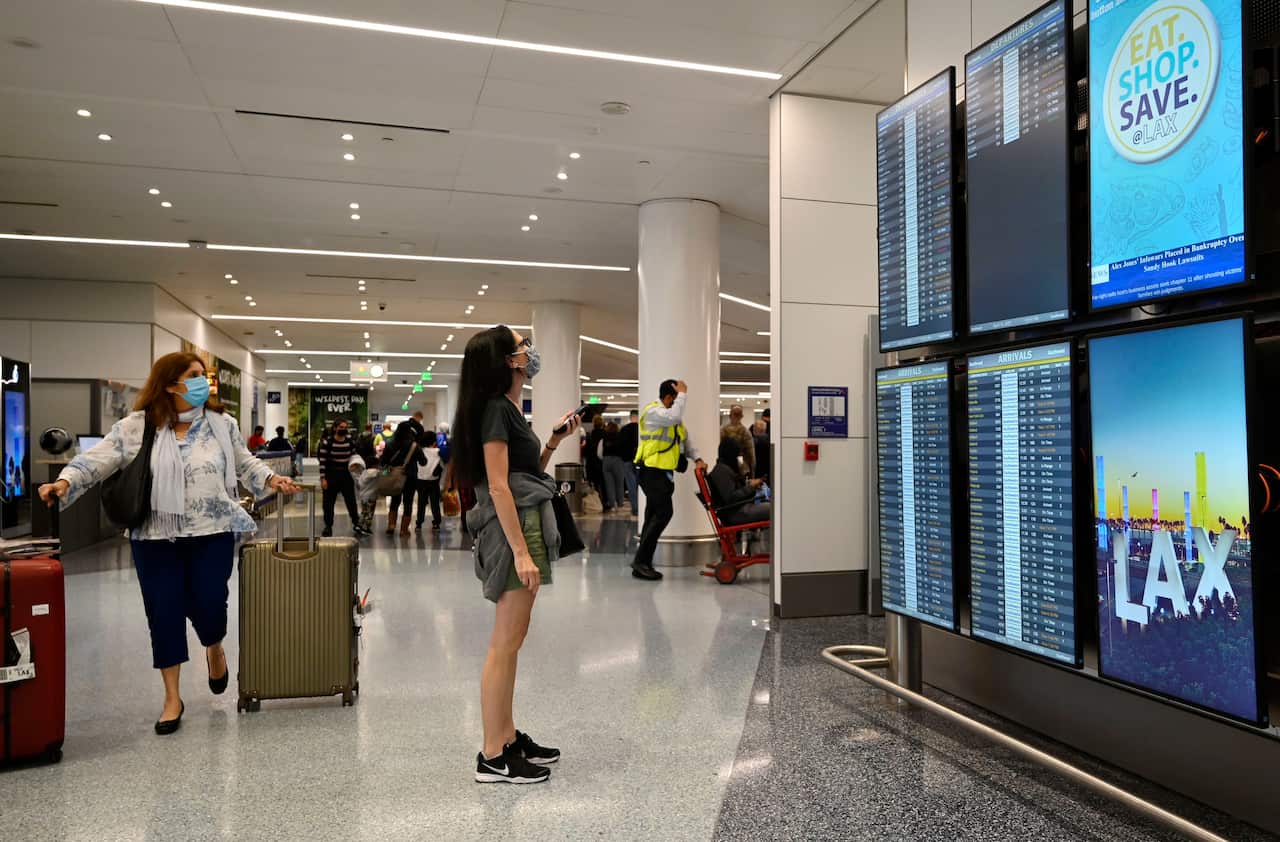 Two women look up at a screen at the airport. 
