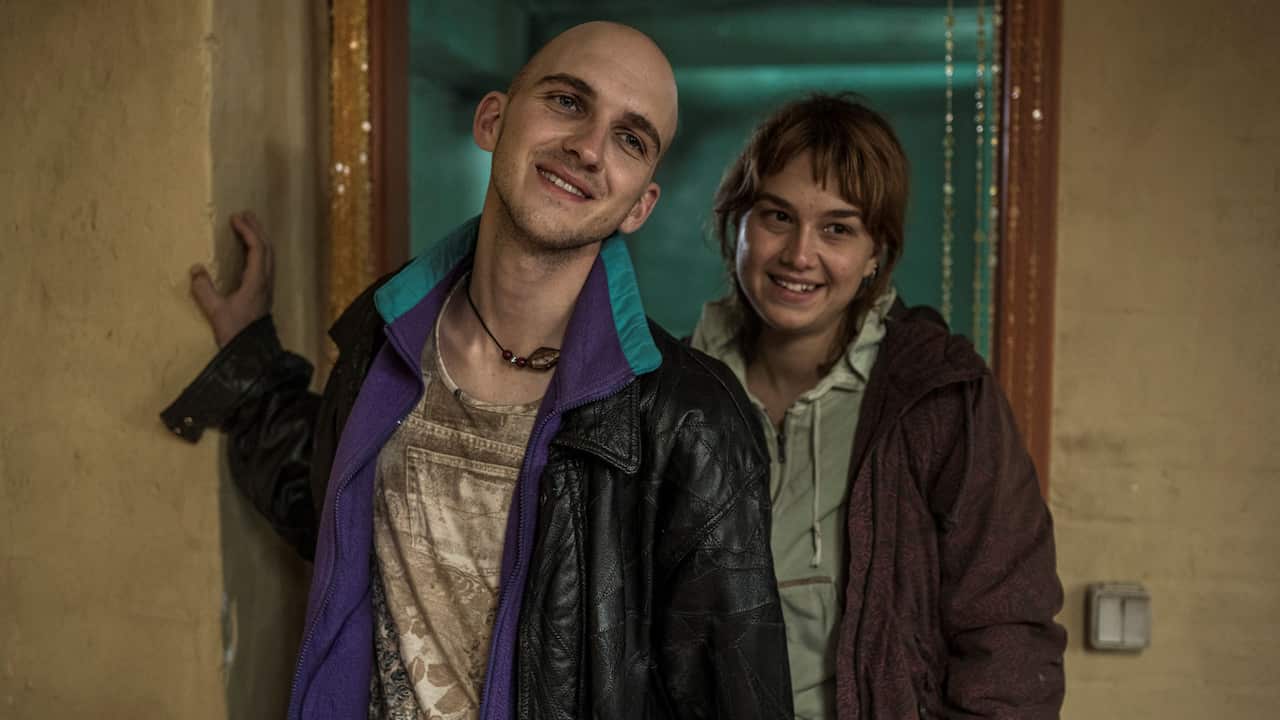 A young man and woman stand smiling in a doorway of a house.jpeg