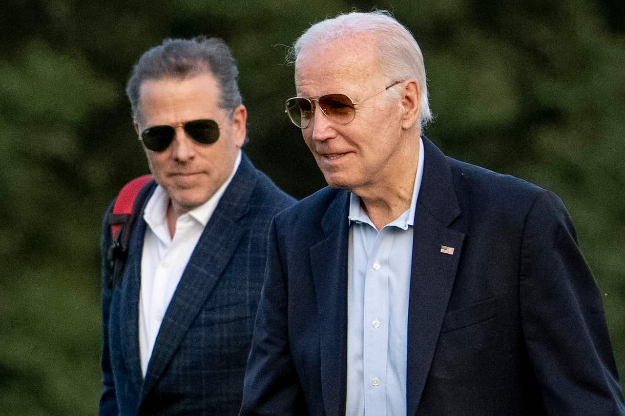 The US President Joe Biden wearing a pair of sunglasses with his son Hunter in the background.