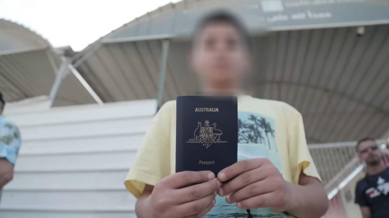 A young boy in a yellow shirt holding an Australian passport