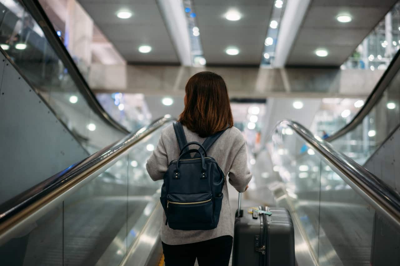 Young woman holding suitcase or baggage with backpack in the international airport.