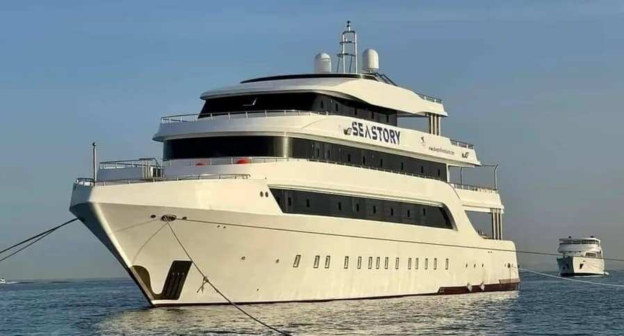 A large white ship, with the words 'Sea Story' inscribed on it, is docked.