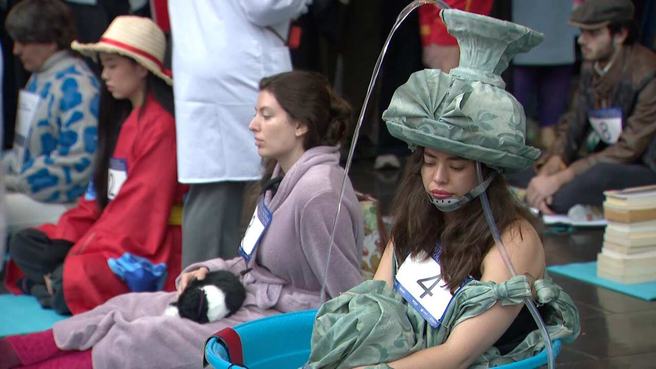 A woman dressed as a working fountain, she has running water pouring from a spout above her head