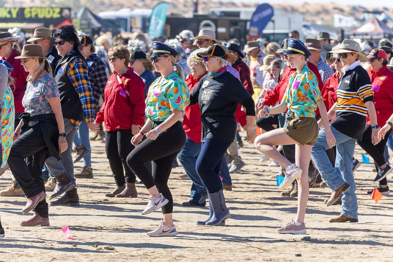 Group of people line dancing in the desert