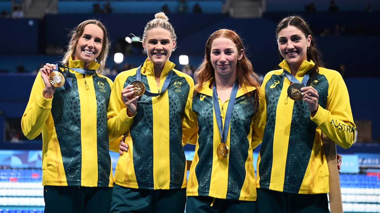Four female swimmers pose for a photograph with their gold medals.