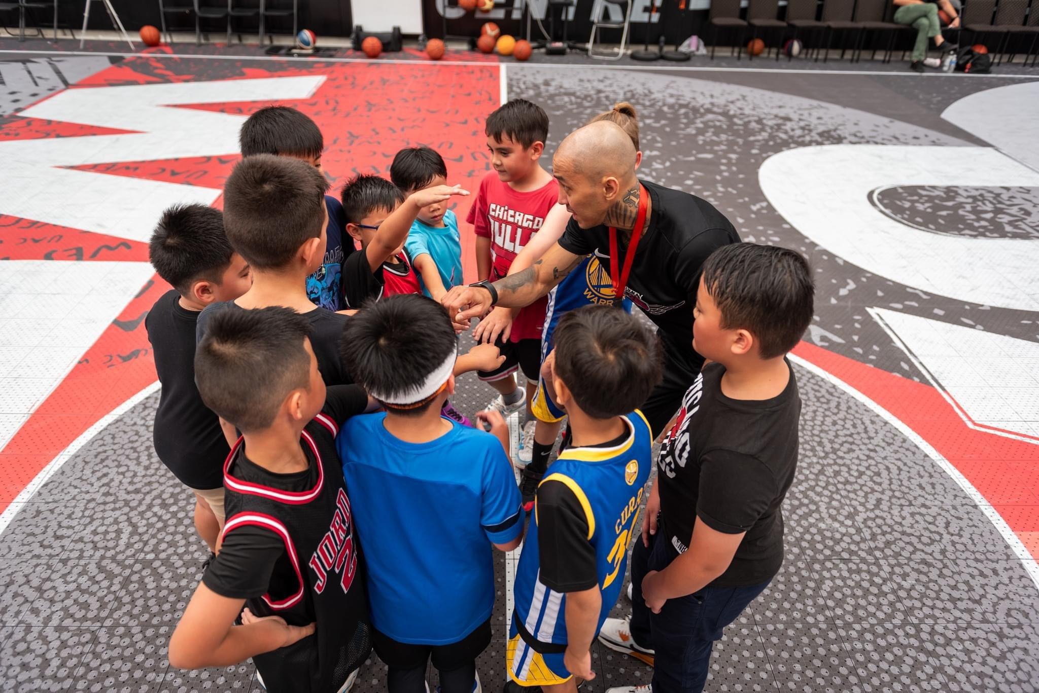 A basketball coach in a huddle with young kids.