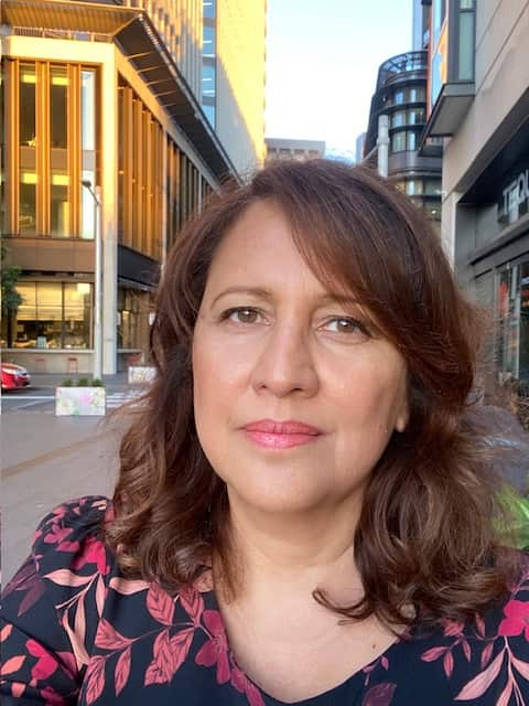 A self-portrait of a woman in the street looking at the camera with a serious expression.