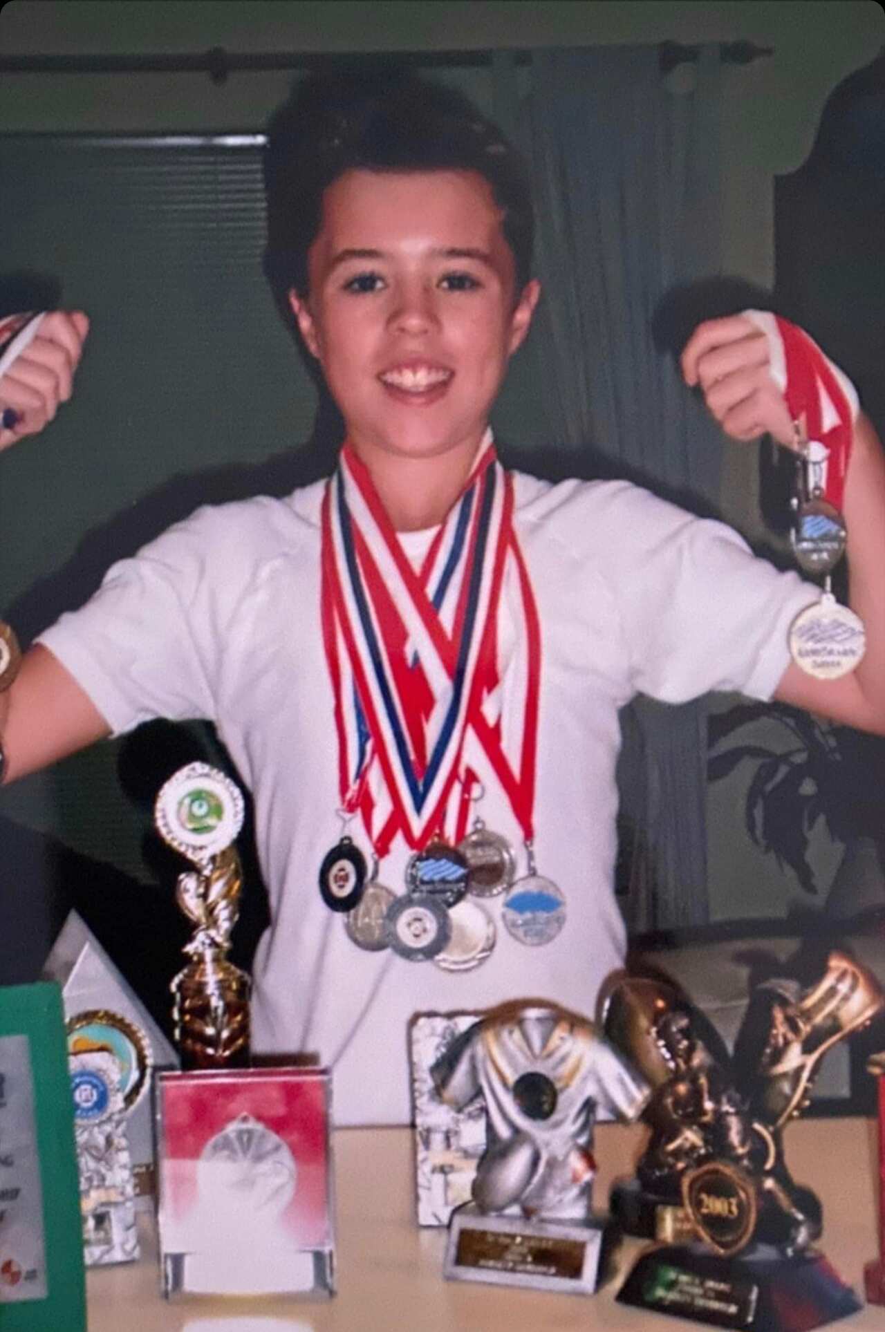 A boy holding various medals 