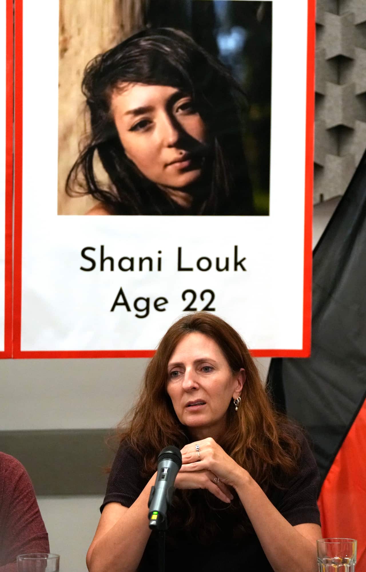 A woman sitting in front of a sign with a photo of her daughter