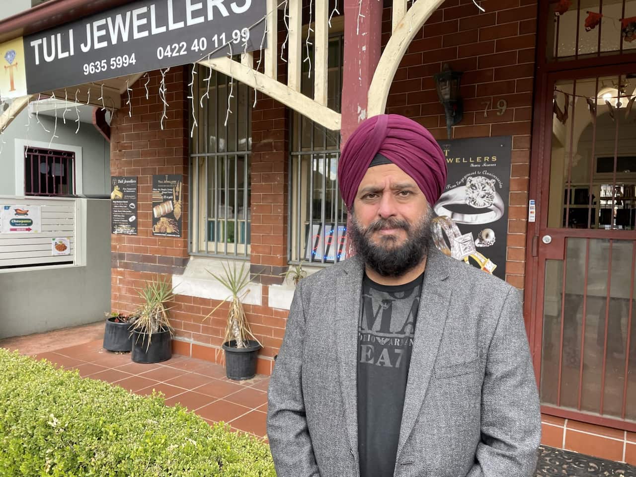 A man stands in front of his shop.