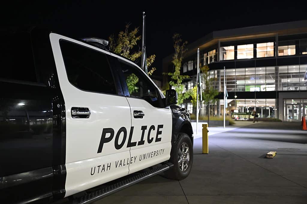 A black and white police vehicle parked in front of a university building at night. 