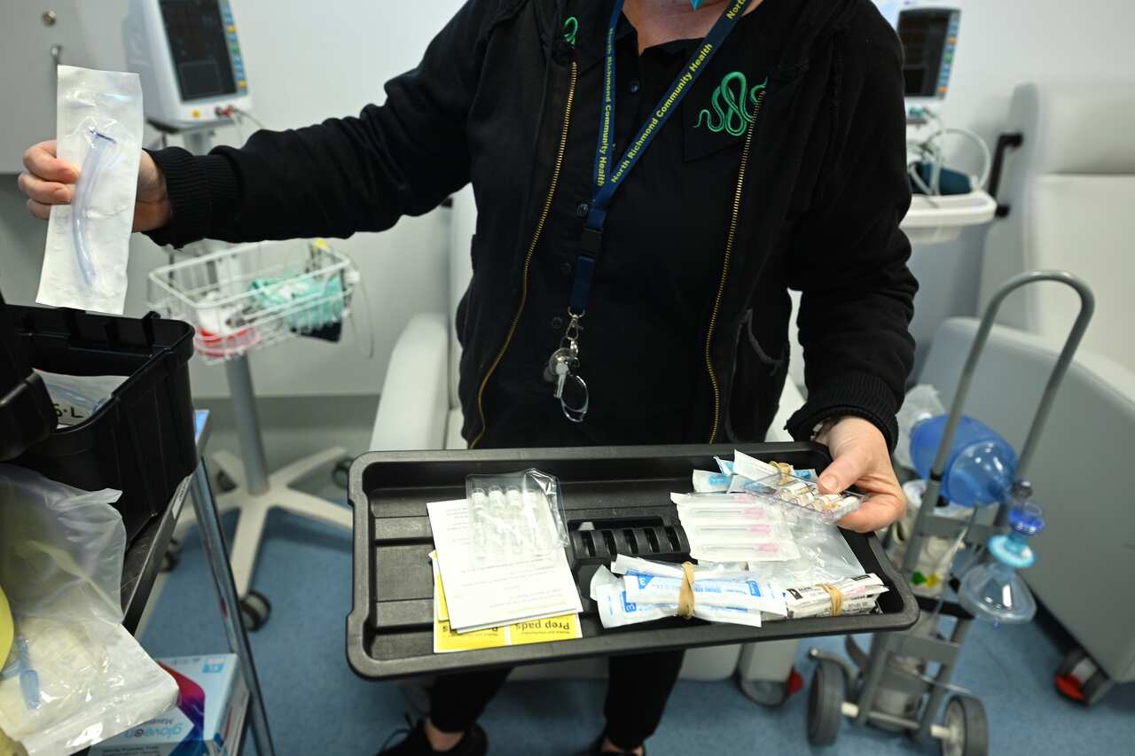 A close up of a person in a small room holding a tray holding medical supplies in packaging
