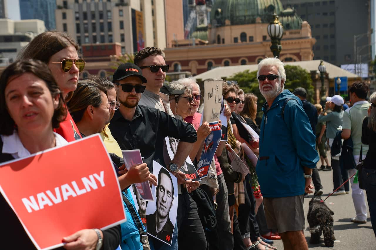 People standing on a bridge holding signs in support of Russian opposition figure Alexei Navalny.