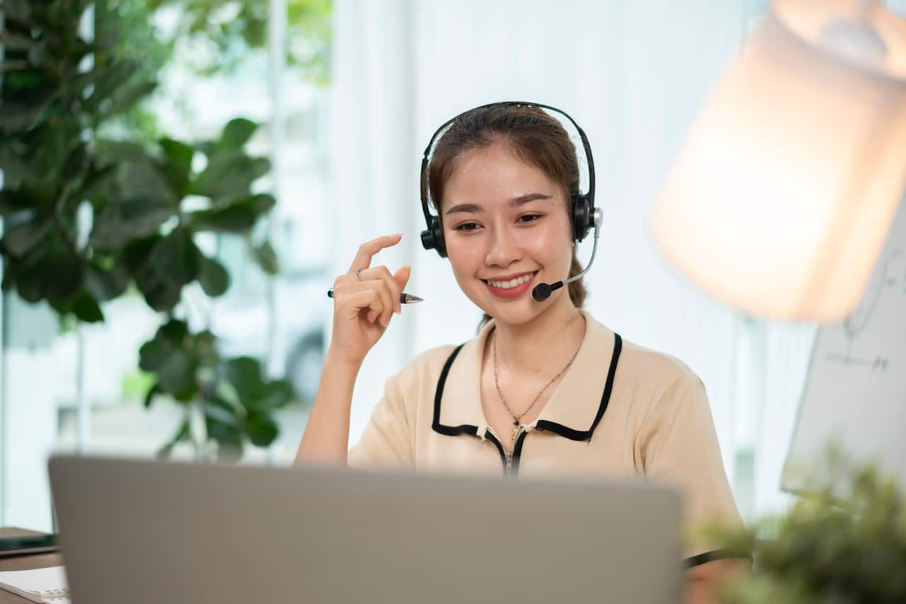 Happy girl interpreter in headset write notes study on laptop: Australia Explained – Translating and interpreting