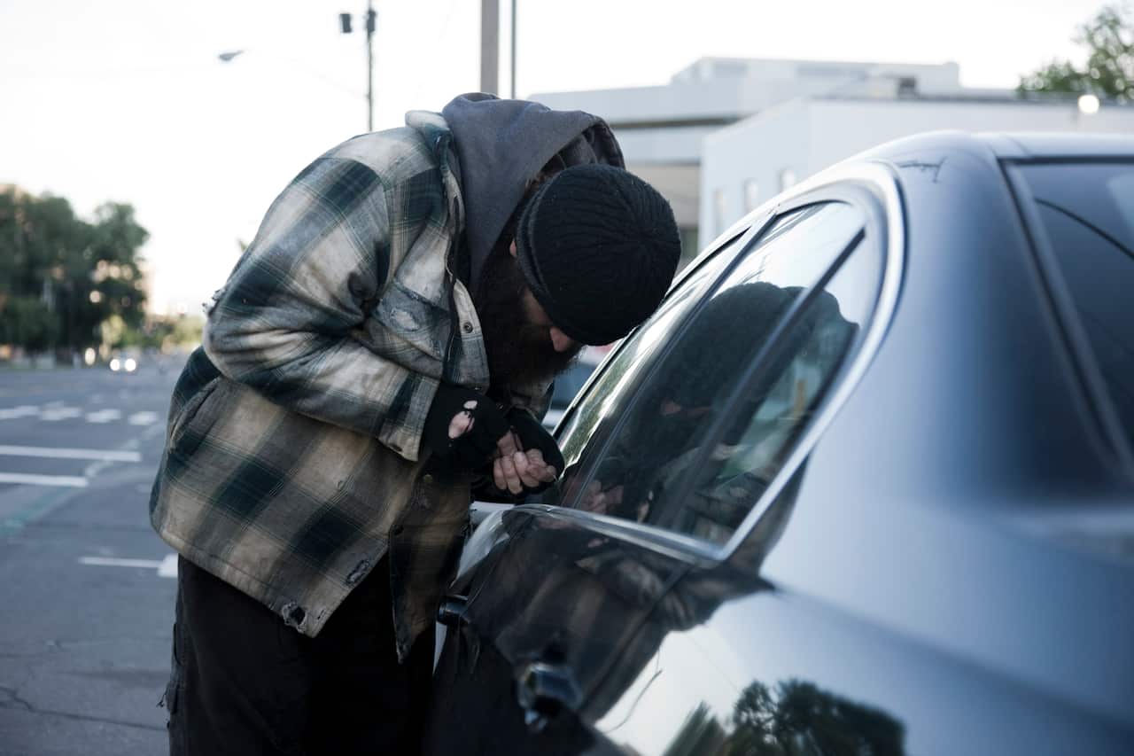 USA, Utah, Salt Lake City, Homeless man breaking into car, side view