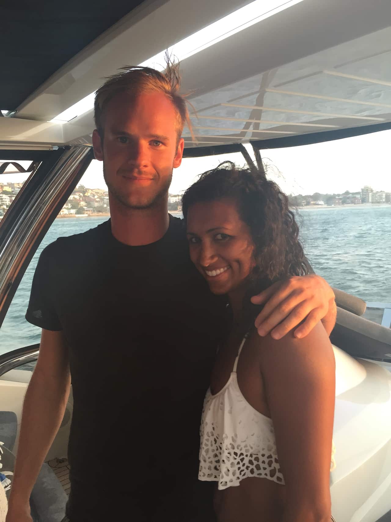 A couple stand on a boat together, embracing and smiling.