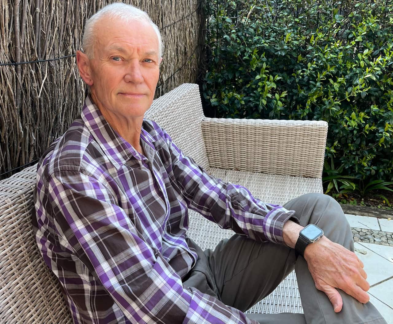 A man sits on a bench in a back yard