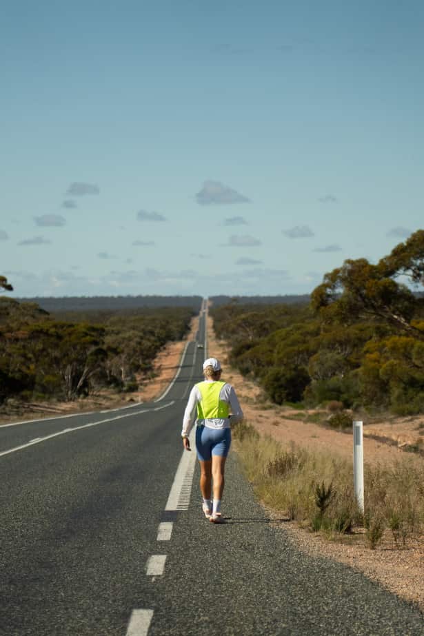 A woman walking down a long and empty road. 