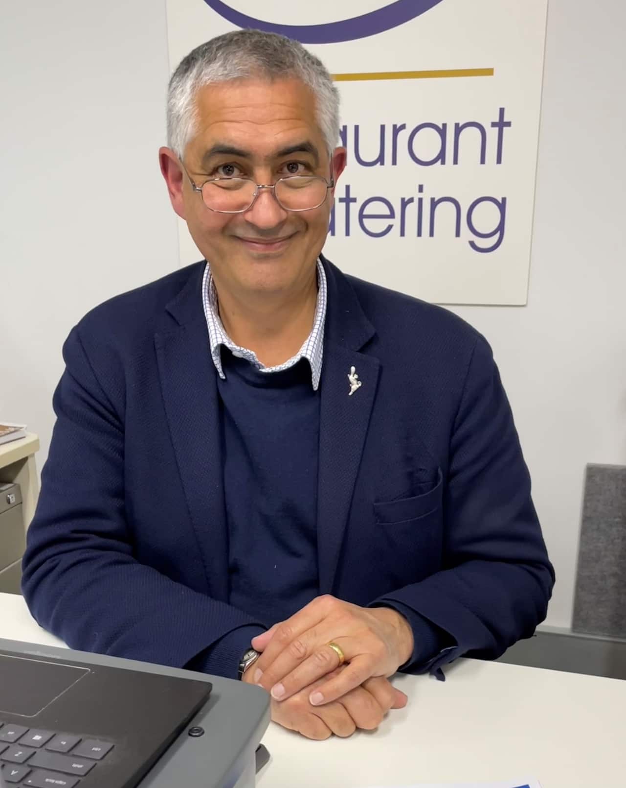 Suresh Manickam sitting at a desk with his hands clasped.