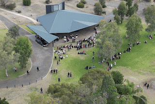 A crowd of people dressed in the colour pink and black attire attend the funeral for Kumanjayi Little Baby.