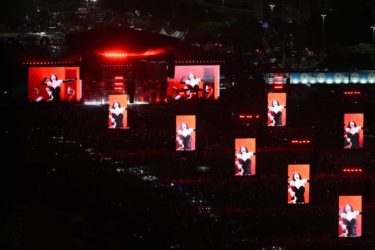 A musician's performance is projected on big screens as she performs during a concert.