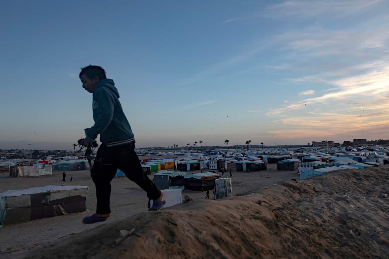A child jumping with tents in the background