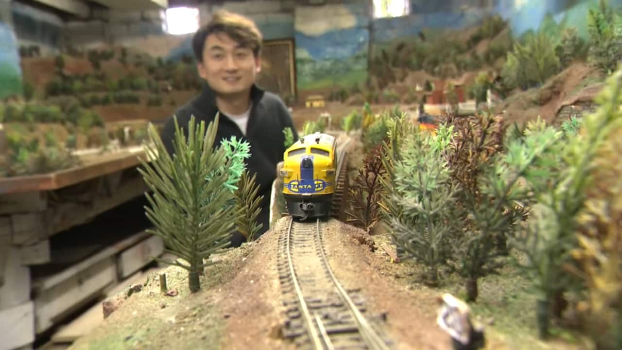 A model train on the tracks of a model set with a person in the background.