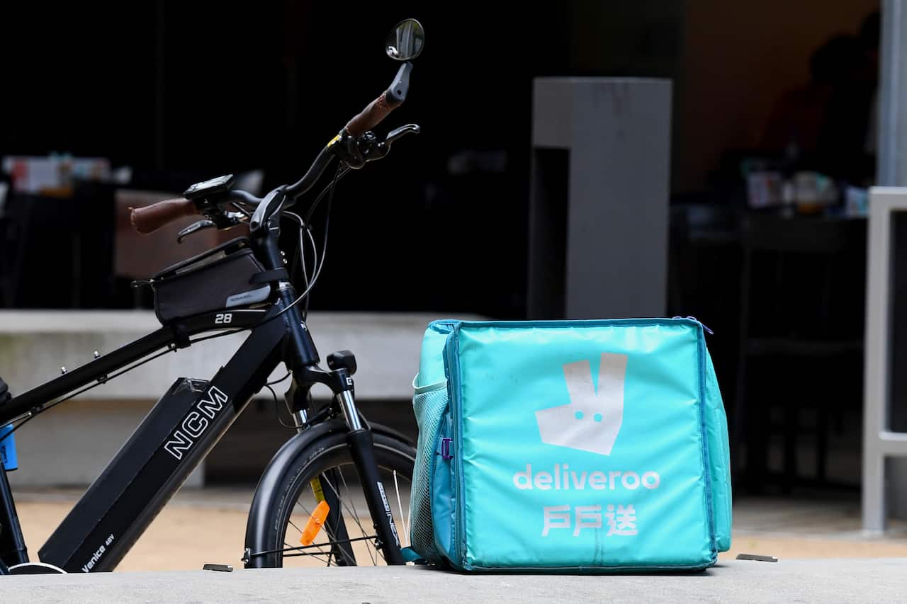 A bag with branding that reads "Deliveroo" placed next to a bike.