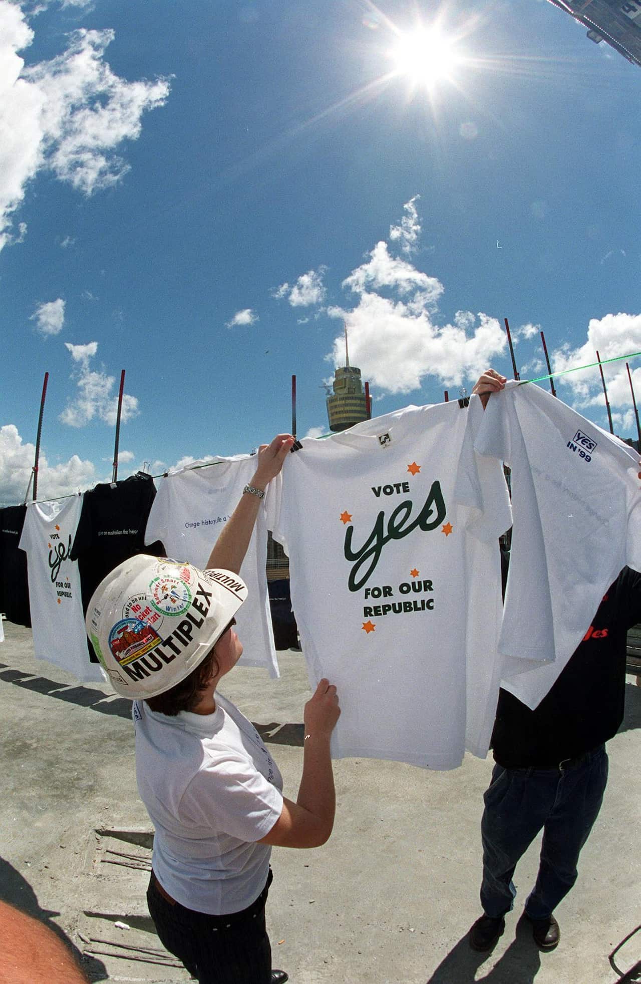 A person in a hard hat, hanging up a t-shirt with a southern cross on it that says 'vote yes for our republic.'