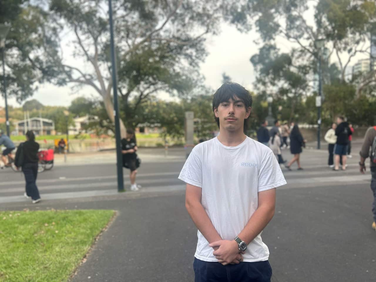 A person wearing a white T-shirt stands with their arms folded.