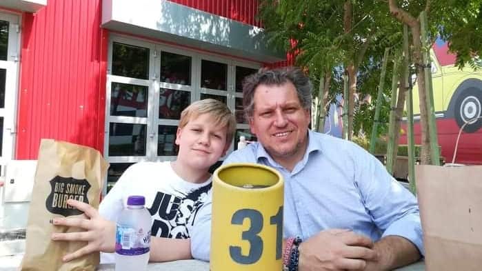 Middle aged man and young boy sitting at a table outside