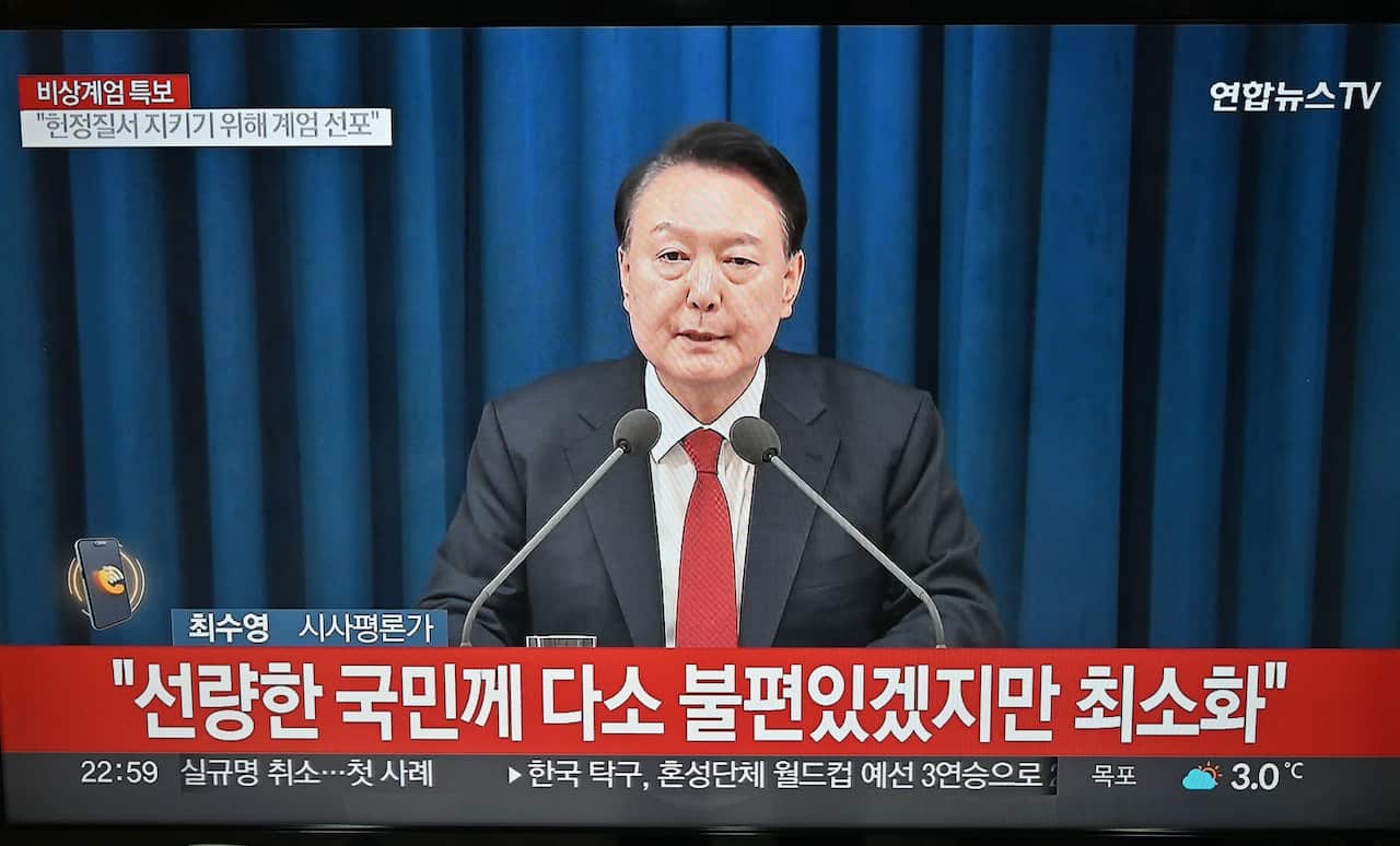 A television screen shows South Korea's President Yoon Suk Yeol speaking during a news broadcast.