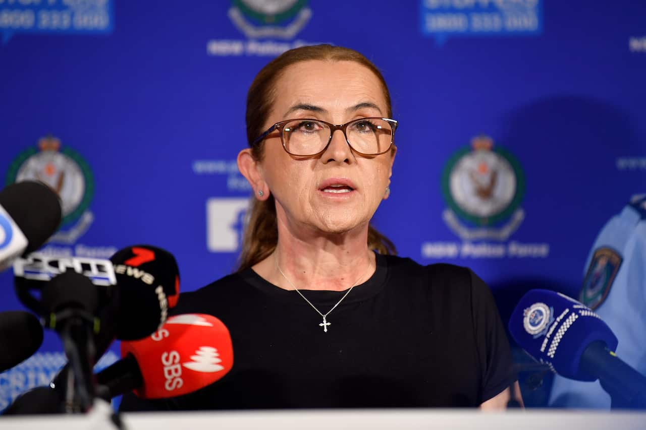 A middle-aged white woman speaking before microphones