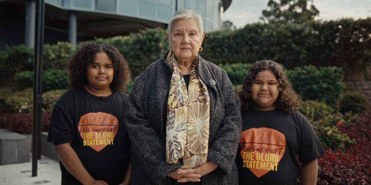Alyawarre woman and Uluru Dialogue Co-Chair Pat Anderson AO with two young Uluru Statement supporters in an ad encouraging Australians to vote "yes" to an Indigenous Voice to Parliament.